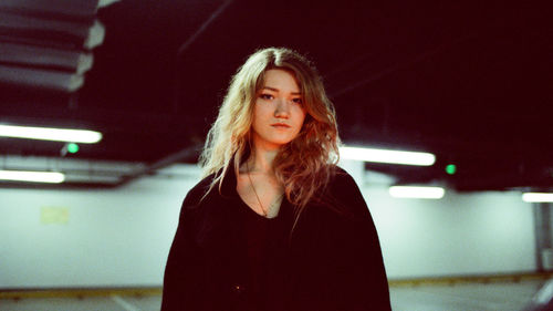 Portrait of beautiful woman standing in illuminated room