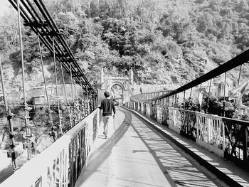 Rear view of people walking on footbridge in city