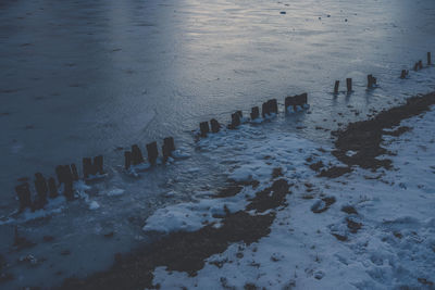 High angle view of wooden posts on beach during winter