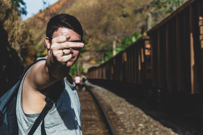 Portrait of young man standing on railroad track