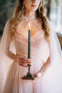 Midsection of bride holding candle