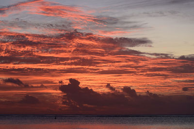 Scenic view of sea against dramatic sky during sunset