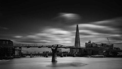 View of bridge and buildings against cloudy sky