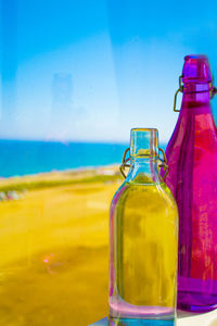 Close-up of beer bottle against blue sea