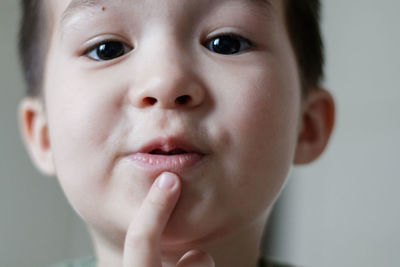 Adorable little asian boy put his finger to his lips and looks down at camera. close up.