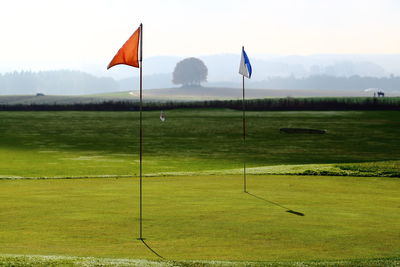 Scenic view of golf flag against sky