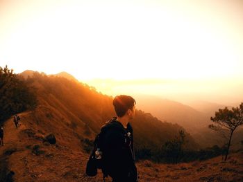 Rear view of man standing on mountain against sky