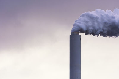 Smoke emitting from chimney against sky