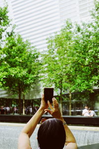 Rear view of woman photographing through smart phone