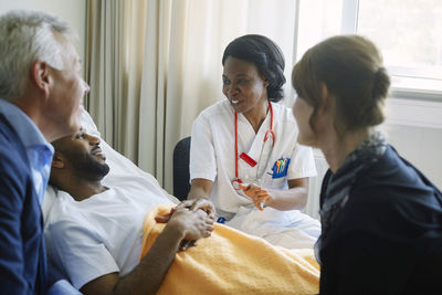Healthcare worker encouraging patient and his family at hospital ward