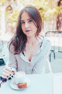 Portrait of young woman with coffee cup in cafe