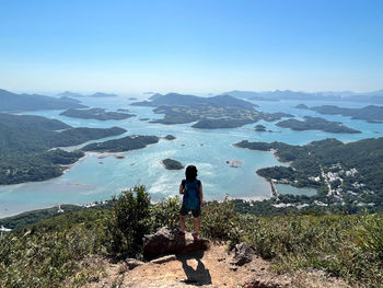 Man standing on rock against blue sky