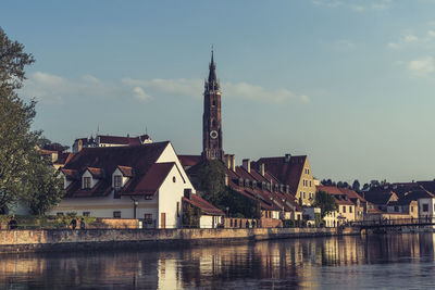 Buildings by river against sky