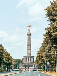 Statue in city against cloudy sky