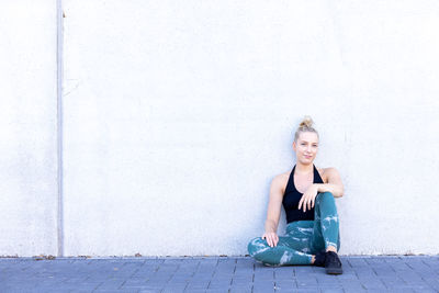 Portrait of young woman standing against wall