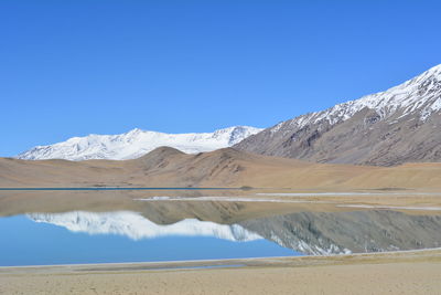 Scenic view of snowcapped mountains against blue sky
