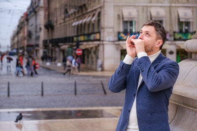 Young woman drinking water while standing in city