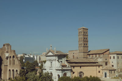 Buildings in city against clear blue sky