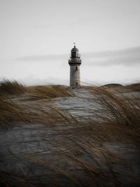 Lighthouse on landscape against sky