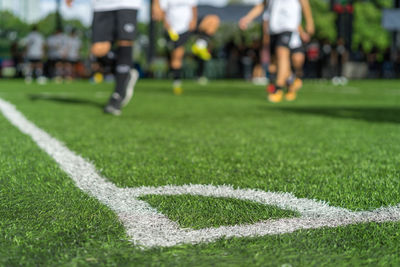 Low section of people playing soccer on field