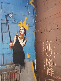 Woman standing by text on wall