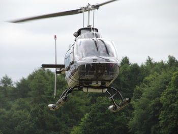 Low angle view of helicopter flying against trees