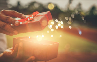 Close-up of hand holding lit candle in box