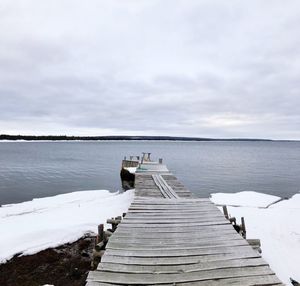 Wooden pier over lake against sky