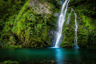 Scenic view of waterfall by mountains