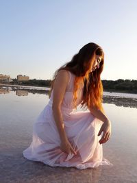 Woman standing in sea against sky