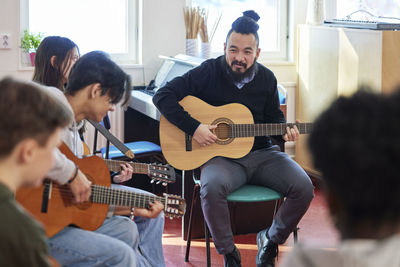 Teenagers attending guitar lesson