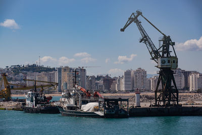 Cranes in city against sky