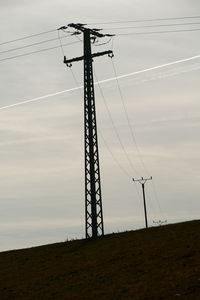 Low angle view of electricity pylon on field against sky