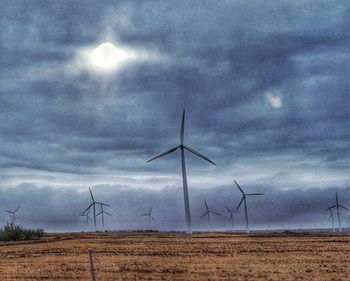 Wind turbines on field against sky