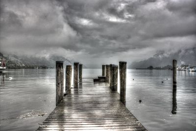 Pier on sea against cloudy sky