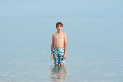 Full length of boy standing in sea