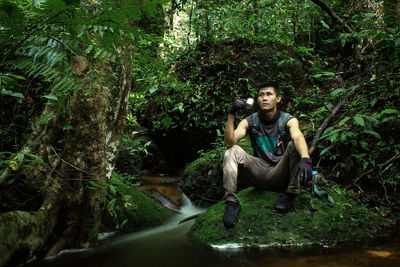 Adventurous male portrait exploring the forest while drinking in river