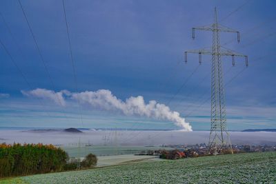 Electricity pylon on field against sky