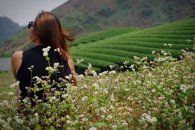 Rear view of woman with flowers on field