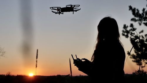 Woman piloting a drone at sunset