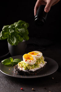 Woman salt a sandwich with avocado and eggs