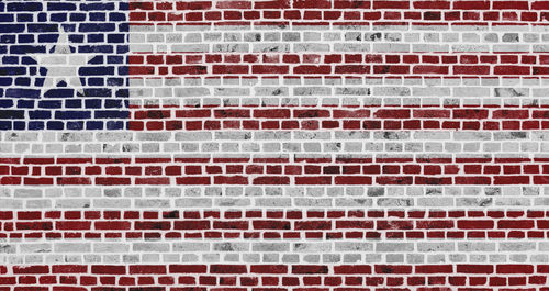 Close-up on a brick wall with the flag of liberia painted on it.