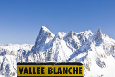 Information sign against snowcapped mountains against sky