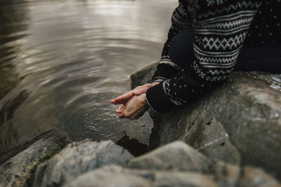 Midsection of female hiker washing hands at lake during vacation