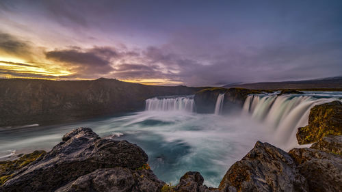 Scenic view of waterfall against sky during sunset