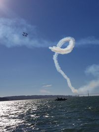 Airplane flying over sea against blue sky