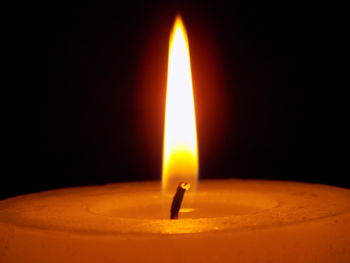 Close-up of lit candle against black background