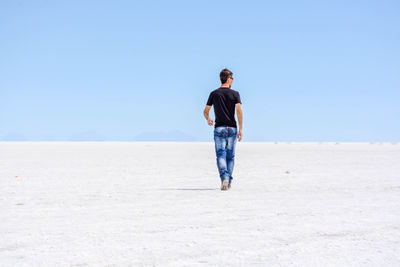 Full length rear view of man walking on beach