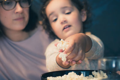 Close-up of girl with mother holding popcorn
