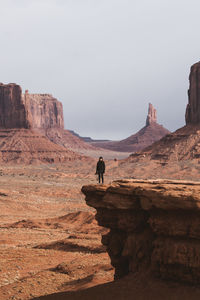 Man on rock formations against sky